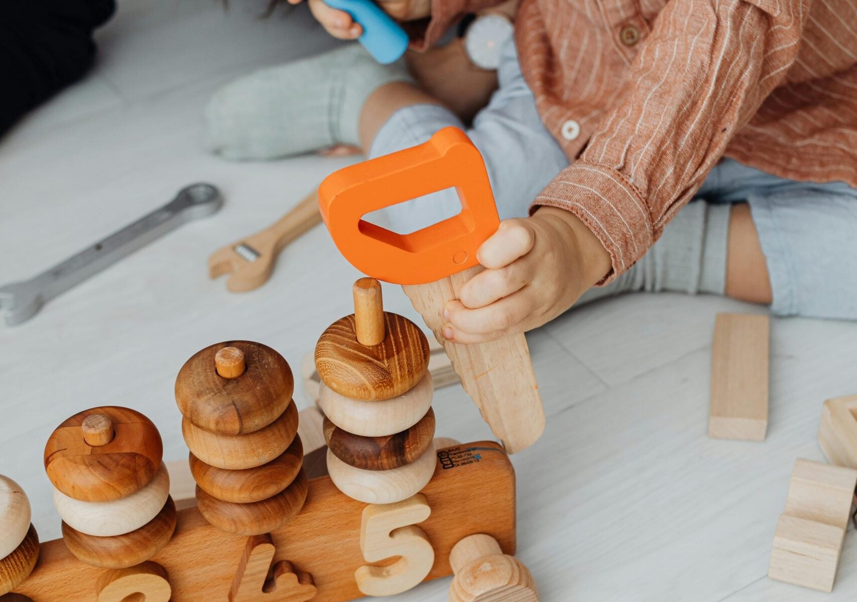 A young child playing indoors with wooden educational toys, enhancing creativity and motor skills.
